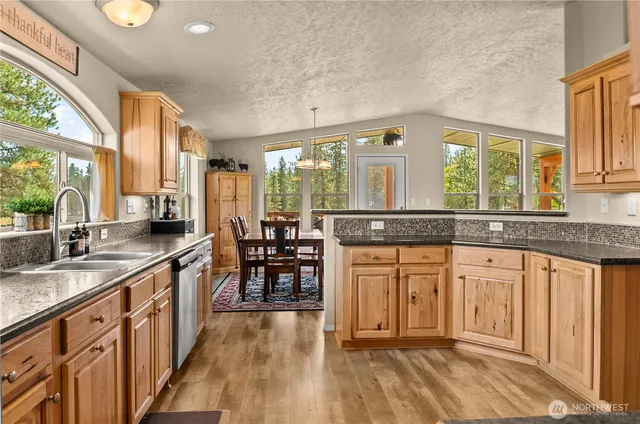 a kitchen with stainless steel appliances granite countertop a stove a sink and a granite counter tops with white cabinets next to a window
