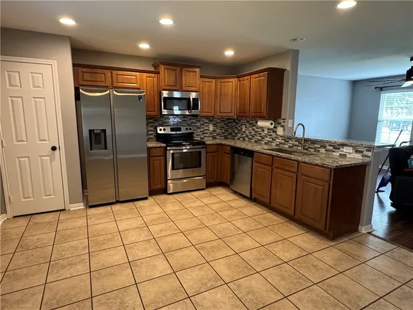a kitchen with stainless steel appliances granite countertop a refrigerator and a stove top oven