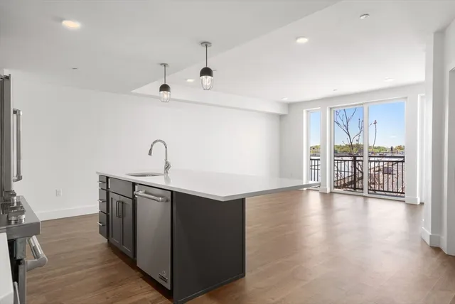 a kitchen with stainless steel appliances granite countertop a sink and wooden floor