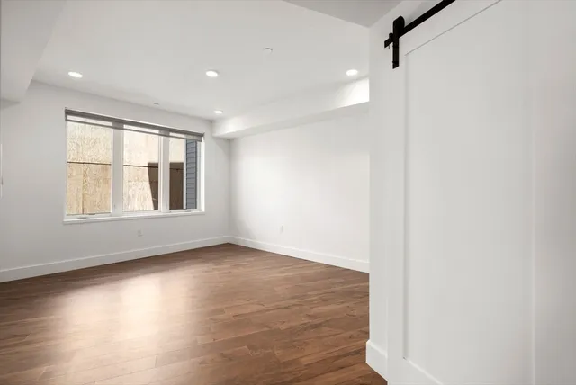 a view of an empty room with wooden floor and a window