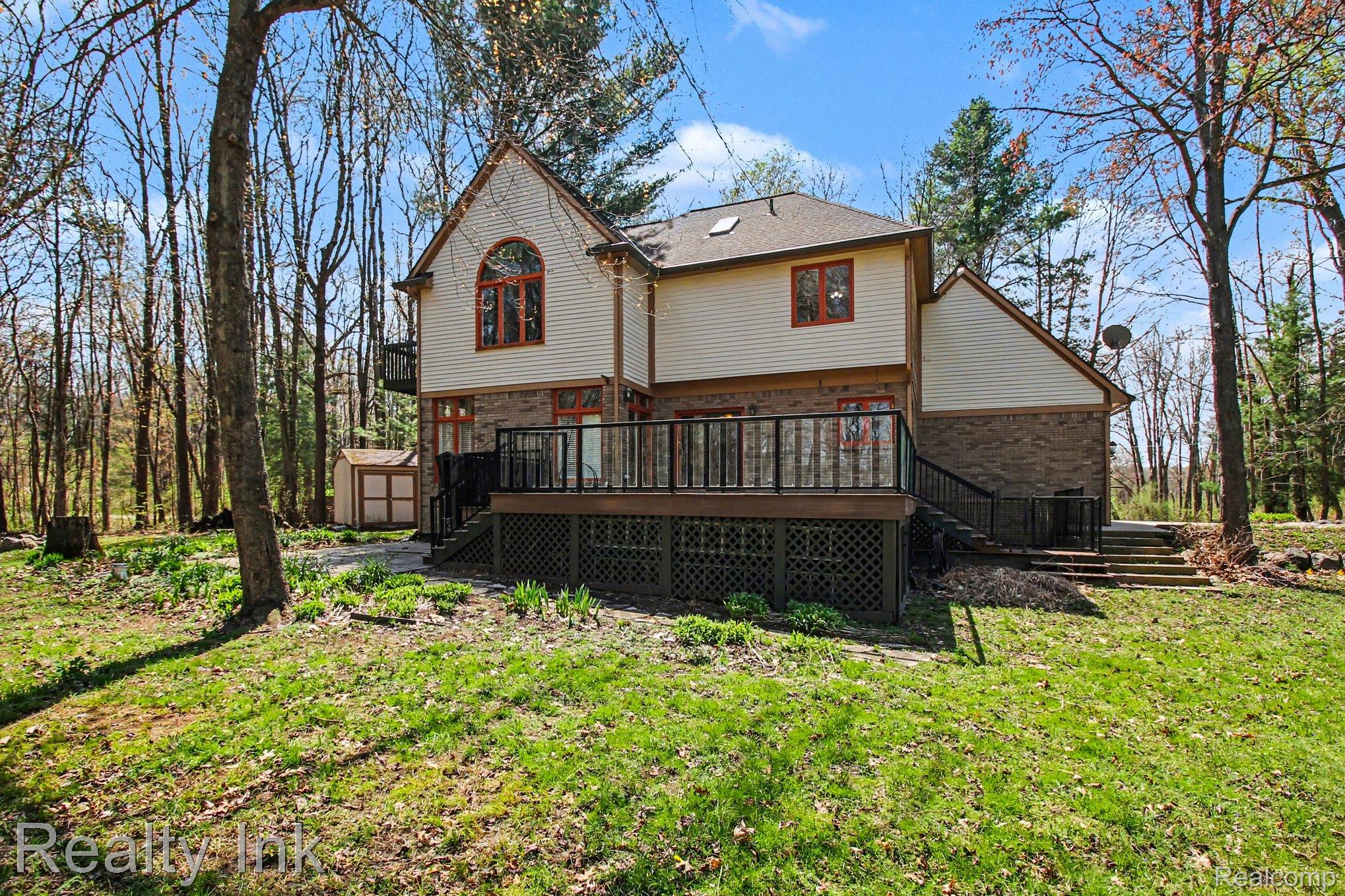 4927 Nature View Court Howell, MI 48843 - Photo 3 of 19 Rear view of property with a large Trex deck, a storage unit, a lawn, and brick siding