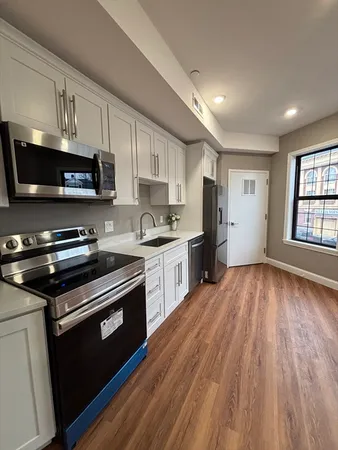 a kitchen with granite countertop a refrigerator stove and white cabinets
