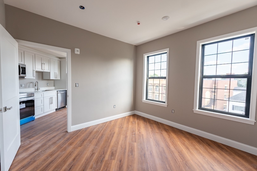13 Nahant Street, Unit 2D Lynn, MA 01902 - Photo 6 of 11 a view of a kitchen and an empty room with wooden floor and a window