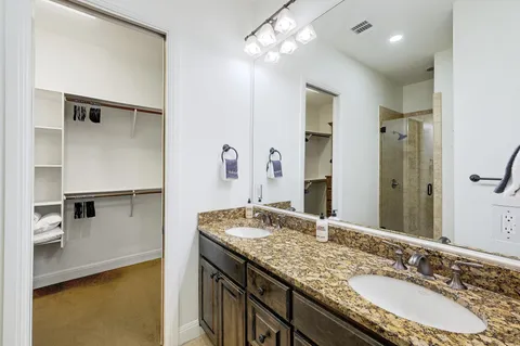 a bathroom with a granite countertop sink a large mirror and a shower