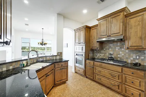 a kitchen with stainless steel appliances granite countertop a sink a stove and a refrigerator