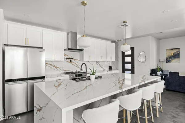 a kitchen with stainless steel appliances kitchen island granite countertop a table chairs and white cabinets