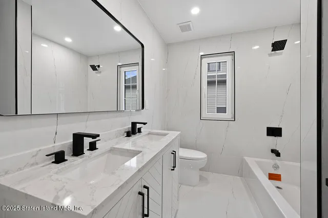 a bathroom with a shower sink vanity mirror and toilet