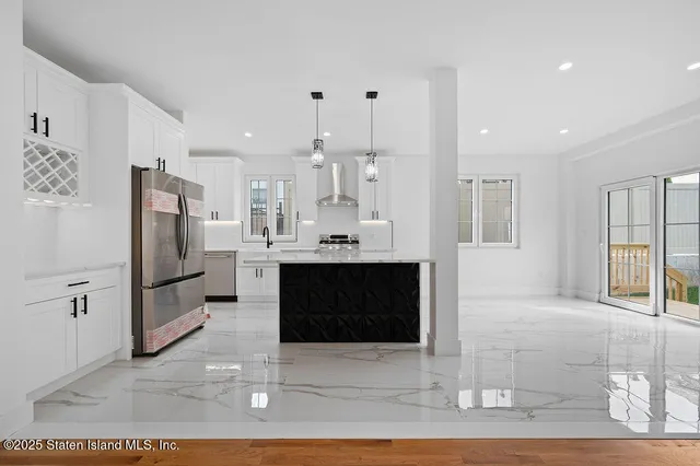 a large white kitchen with stainless steel appliances kitchen island granite countertop a refrigerator and a stove top oven