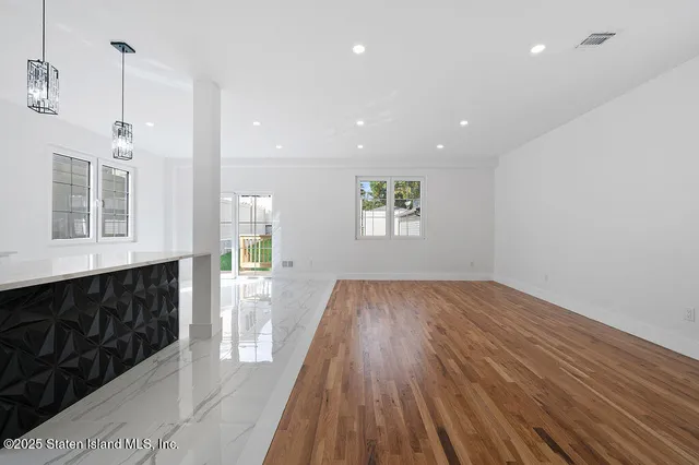 a view of empty room with wooden floor and kitchen