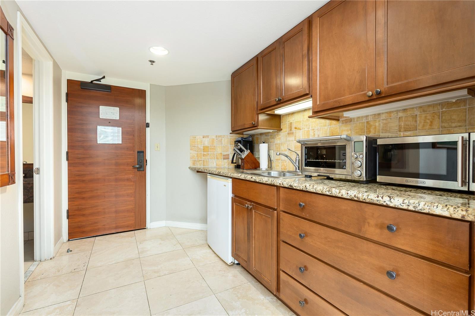2045 Kalakaua Avenue, Unit 604 Honolulu, HI 96815 - Photo 9 of 24 a kitchen with granite countertop cabinets stainless steel appliances and wooden cabinets