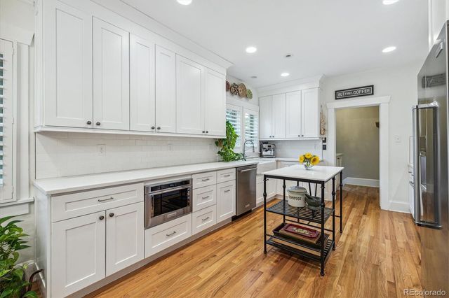 a kitchen with stainless steel appliances a stove a sink cabinets and wooden floor