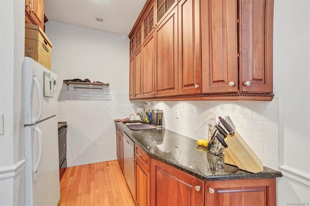 a kitchen with stainless steel appliances granite countertop a sink a refrigerator and a stove with wooden floor