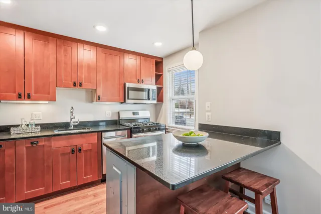 a kitchen with a kitchen island hardwood floor sink stove dining table and chairs