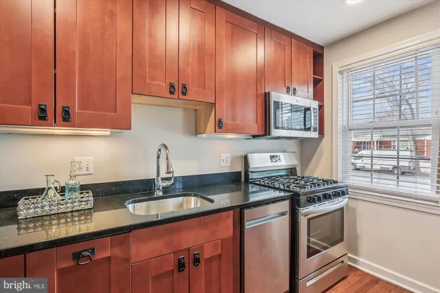 a kitchen with stainless steel appliances granite countertop a sink stove and cabinets