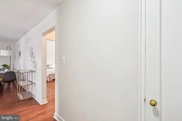 a view of a hallway with wooden floor table and chairs