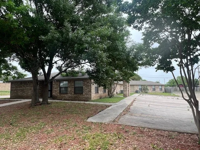 a view of a white house with a large tree
