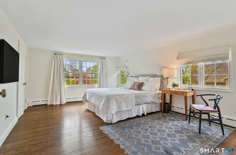 a spacious bedroom with a bed and wooden floor