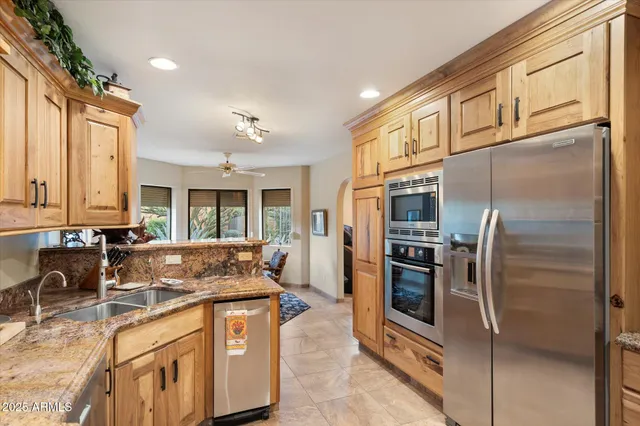 a kitchen with stainless steel appliances granite countertop a refrigerator a stove and a sink
