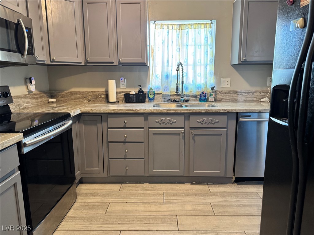 1409 Joshua Way Las Vegas, NV 89101 - Photo 3 of 15 Kitchen featuring gray cabinetry, stainless steel appliances, and light wood-style floors