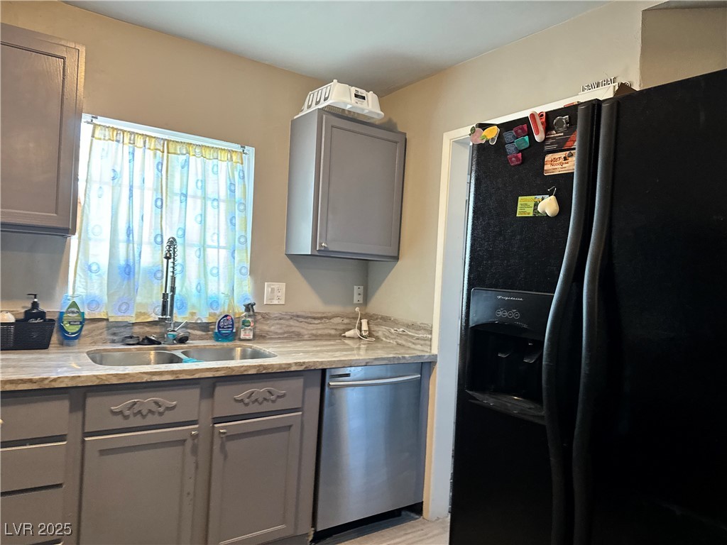 1409 Joshua Way Las Vegas, NV 89101 - Photo 5 of 15 Kitchen featuring gray cabinets, black fridge, stainless steel dishwasher, and light wood-style floors