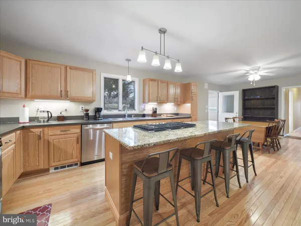 a dining hall with stainless steel appliances kitchen island granite countertop a dining table chairs and granite counter tops