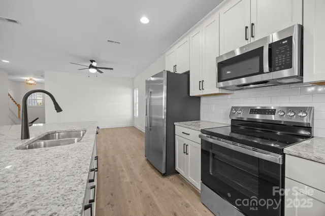 a kitchen with stainless steel appliances granite countertop a stove microwave and sink