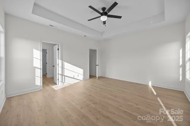 a view of empty room with wooden floor and ceiling fan