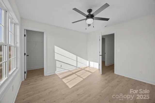 an empty room with ceiling fan and windows