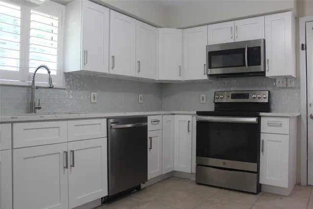 a kitchen with stainless steel appliances granite countertop a refrigerator and a stove top oven