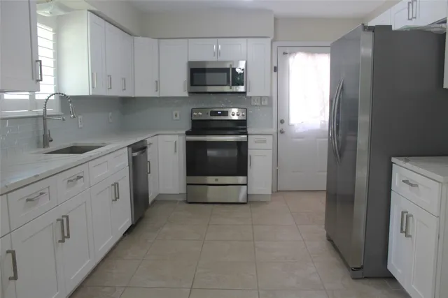 a kitchen with white cabinets and black appliances