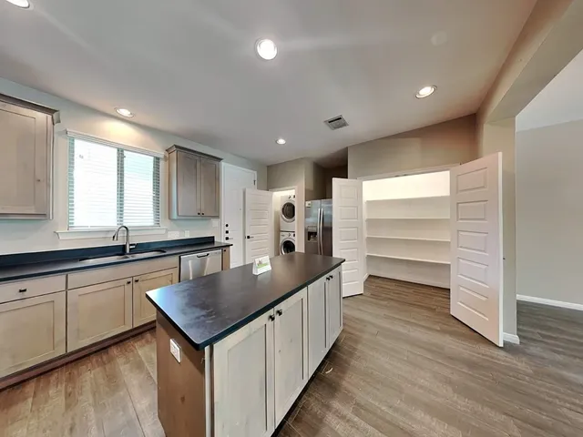 a kitchen with granite countertop stainless steel appliances a sink window and cabinets