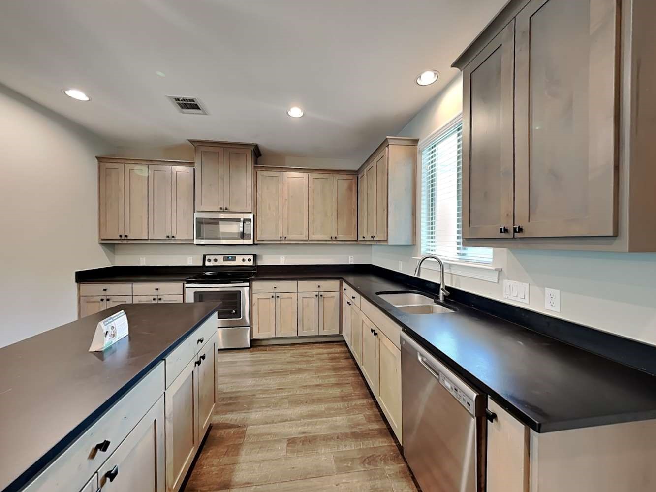 179 Holly Street, Unit 102 Georgetown, TX 78626 - Photo 8 of 17 a kitchen with granite countertop stainless steel appliances a sink window and cabinets