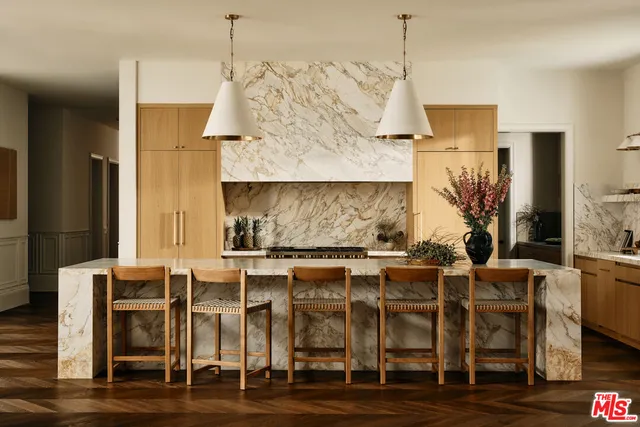 a dining room with furniture wooden floor kitchen view and windows