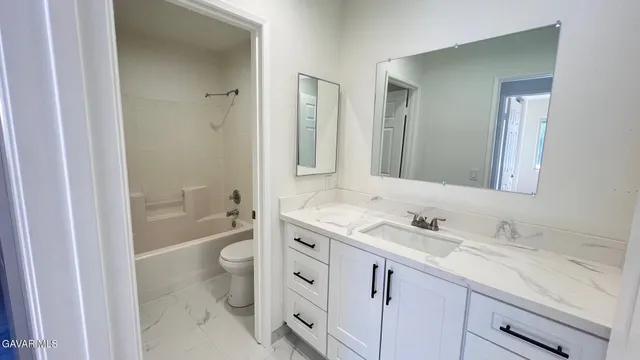 a bathroom with a granite countertop sink a toilet and a large mirror
