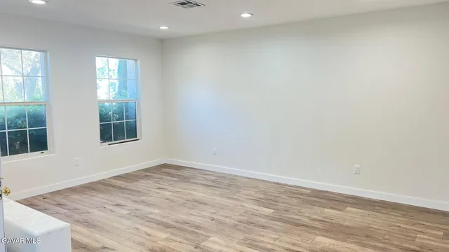 an empty room with wooden floor and windows