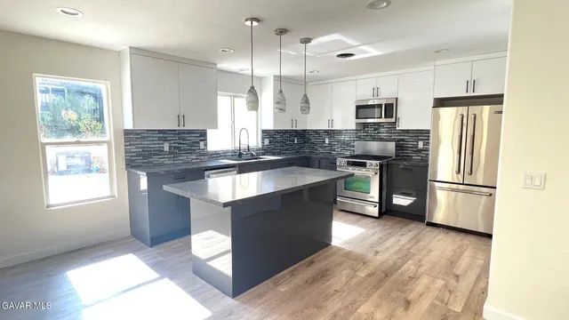 a kitchen with stainless steel appliances granite countertop a stove a refrigerator a sink a oven and a refrigerator with wooden floor