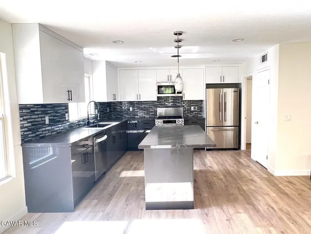 a kitchen with kitchen island a counter top space a stainless steel appliances and cabinets