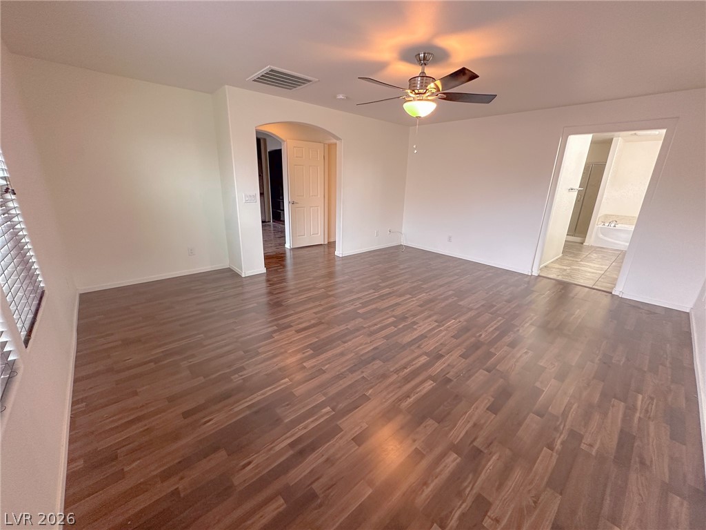 10934 Ketchikan Street Las Vegas, NV 89179 - Photo 12 of 30 Unfurnished room featuring arched walkways, ceiling fan, and dark wood-type flooring