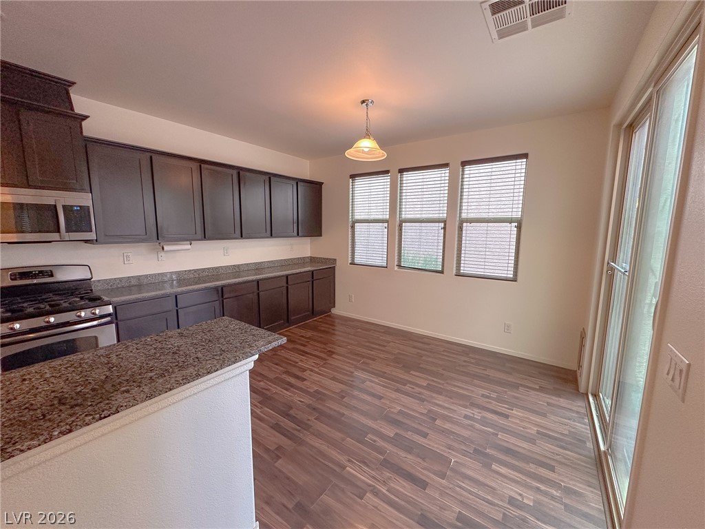 10934 Ketchikan Street Las Vegas, NV 89179 - Photo 23 of 30 Kitchen with stainless steel appliances, dark wood-style flooring, hanging light fixtures, dark wood finish cabinetry, and light stone countertops