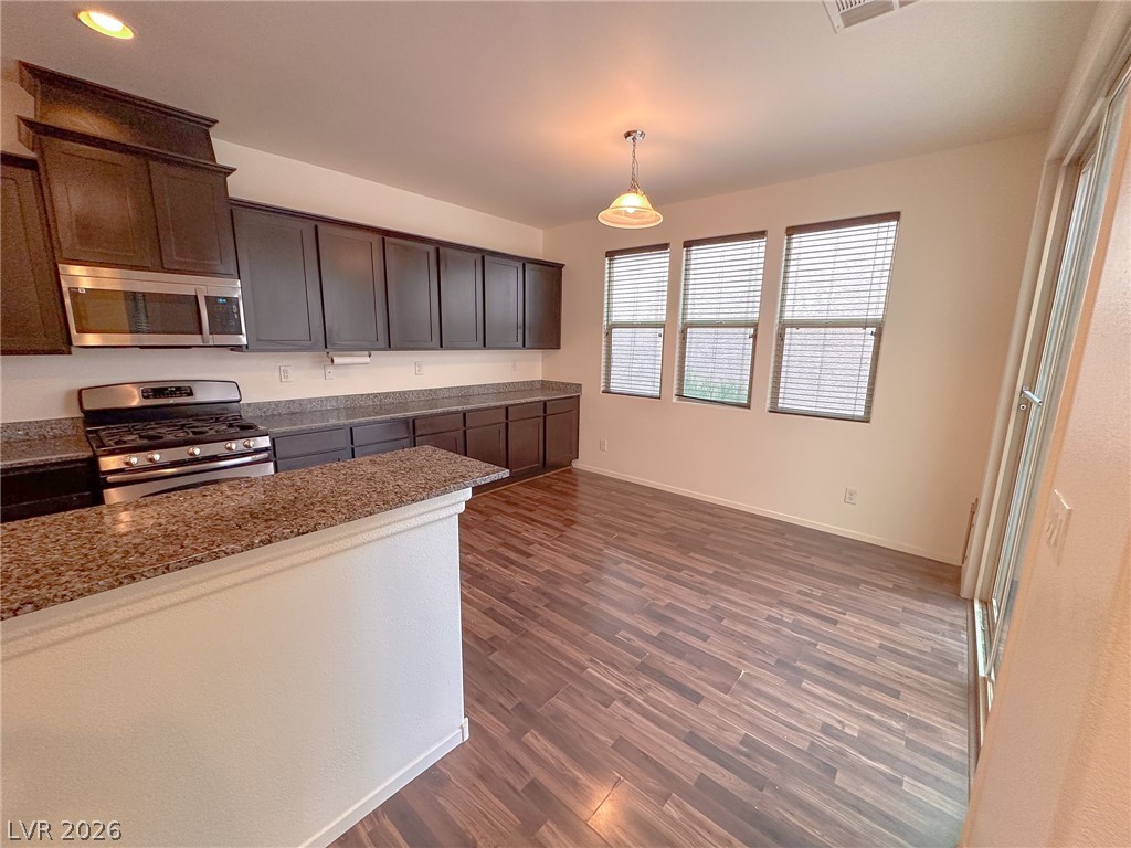 10934 Ketchikan Street Las Vegas, NV 89179 - Photo 24 of 30 Kitchen with stainless steel appliances, dark wood finished floors, decorative light fixtures, light stone countertops, and dark wood finish cabinetry
