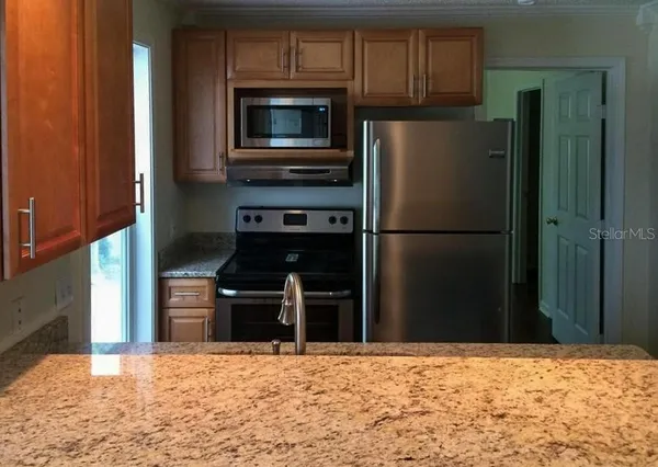 a kitchen with stainless steel appliances kitchen island granite countertop a refrigerator and a stove top oven