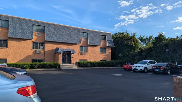 a front view of a house with lots of cars parked on road
