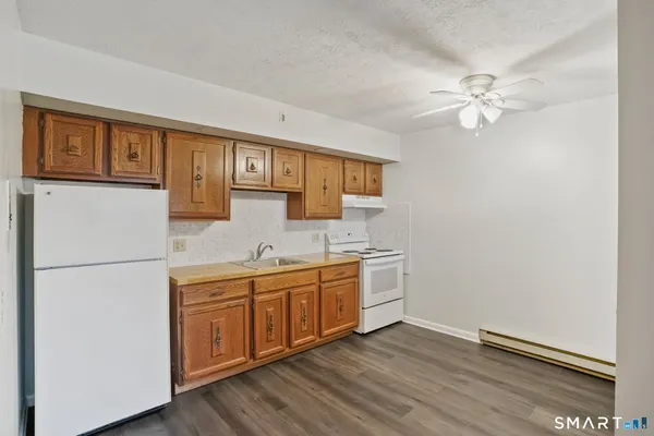a kitchen with a refrigerator a sink and dishwasher with wooden floor