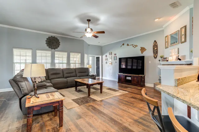 a living room with furniture a flat screen tv and kitchen view