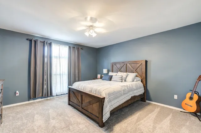 a large bed sitting in a bedroom next to a window and a chandelier
