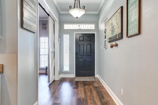 a view of a hallway with wooden floor and a chandelier