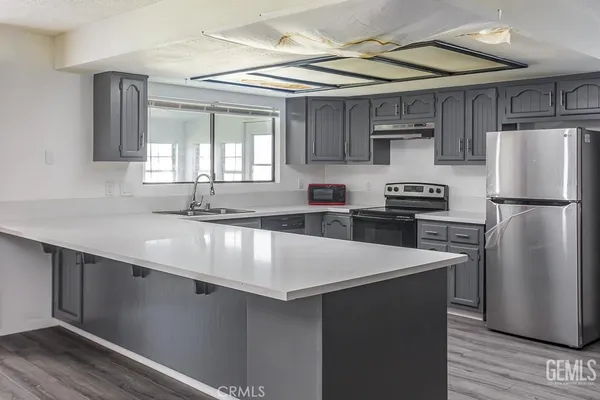 a kitchen with stainless steel appliances a refrigerator a sink a stove a microwave and wooden cabinets