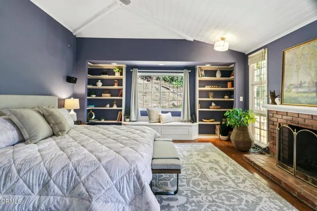 a spacious bedroom with a bed a fireplace and a large window with outer view