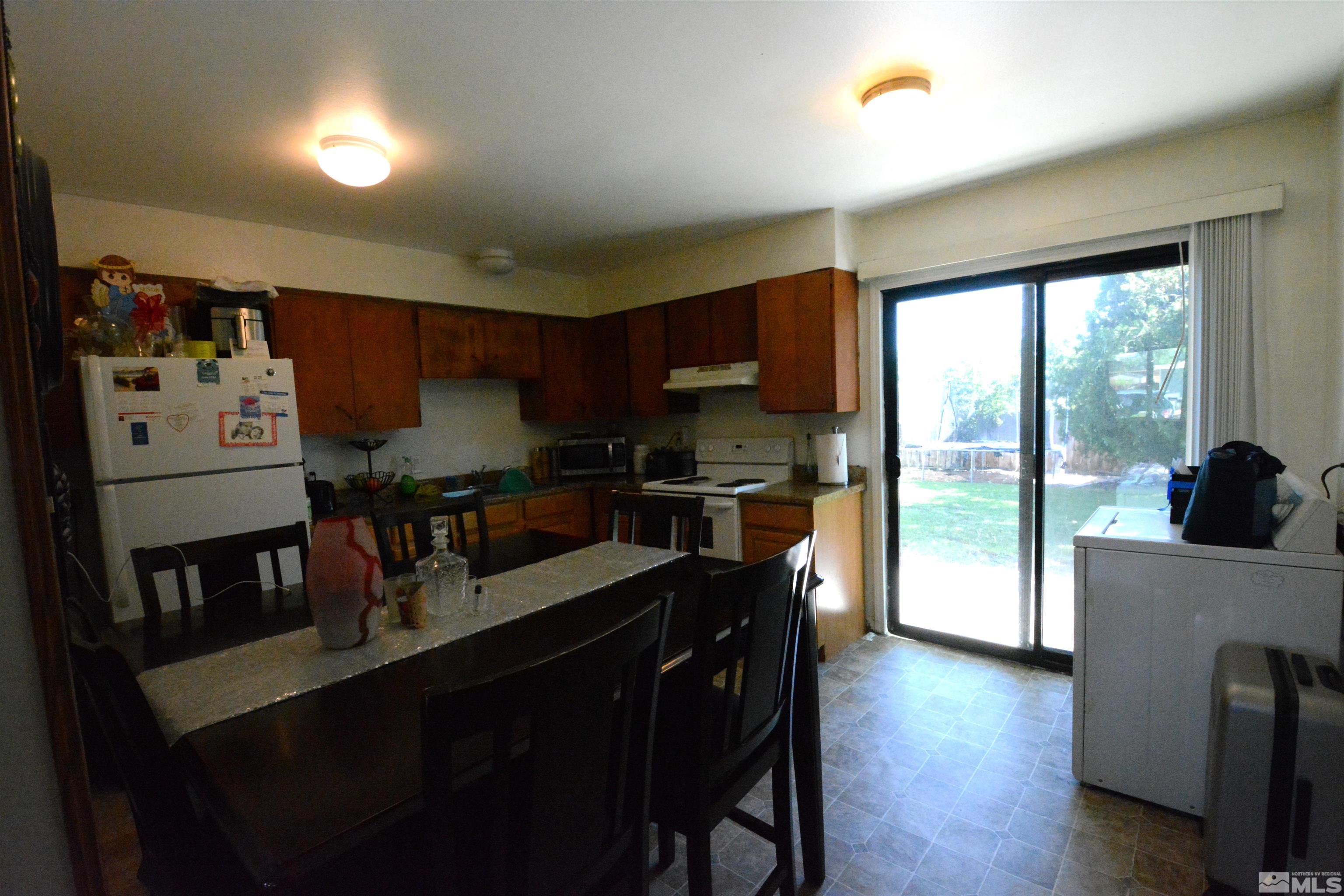 1930 Trainer Way Reno, NV 89512 - Photo 15 of 24 a kitchen with stainless steel appliances granite countertop a refrigerator a sink dishwasher a stove and a dining table with wooden floor
