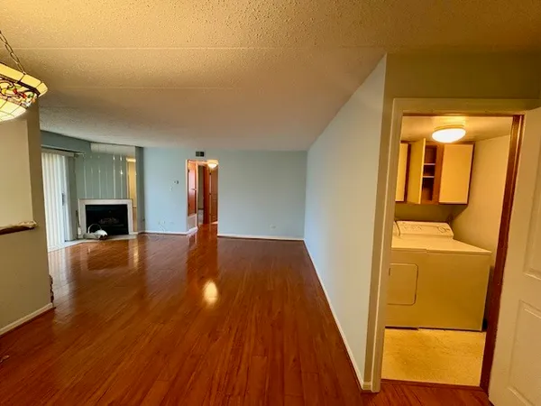 a view of an empty room with wooden floor fireplace and a window